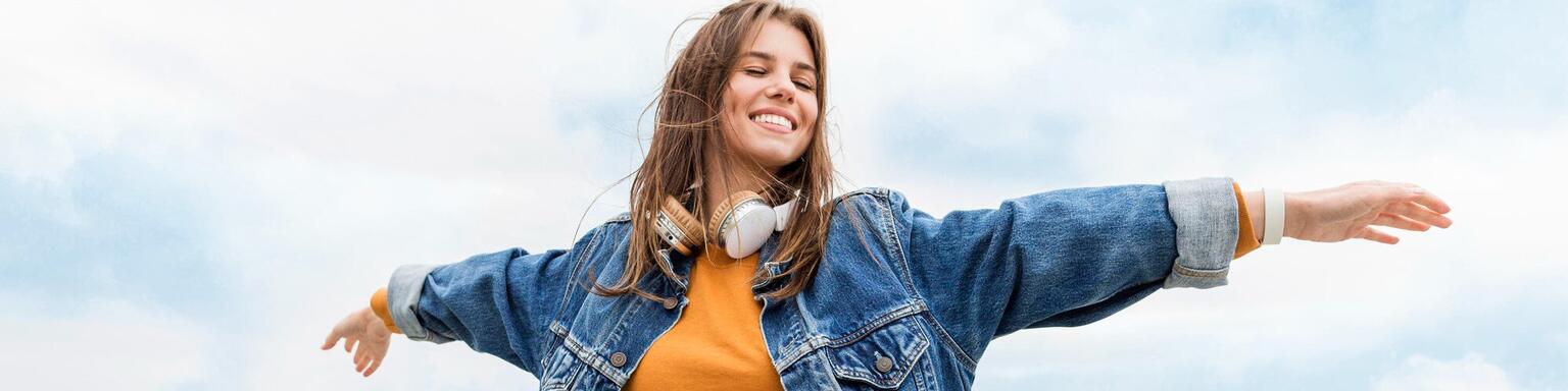Woman outdoors with arms outstretched and headphones on